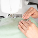 Female Hands Stitching White Fabric On Modern Sewing Machine At Workplace In Atelier - PhotoDune Item for Sale