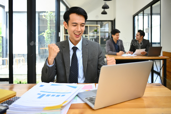 Happy male marketing business manager looking at laptop screen, celebrating business success. - Stock Photo - Images
