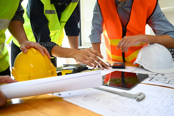 Team of architects wearing reflective jackets discussing construction process together. - Stock Photo - Images