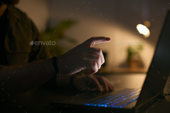 Close Up Of Man Using Laptop At Home At Night With Finger Reaching Out To Touch Screen - Stock Photo - Images