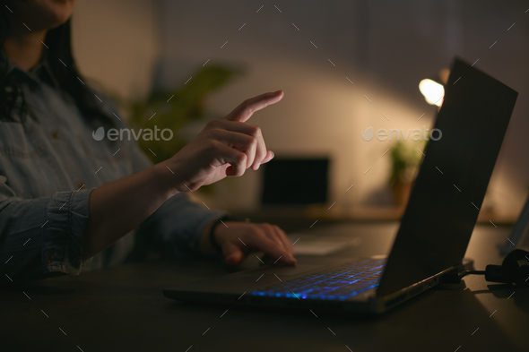 Close Up Of Woman Using Laptop At Home At Night With Finger Reaching Out To Touch Screen - Stock Photo - Images