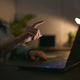Close Up Of Woman Using Laptop At Home At Night With Finger Reaching Out To Touch Screen - PhotoDune Item for Sale