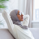 Young muslim woman resting at home with eyes closed hands behind head napping sitting on sofa - PhotoDune Item for Sale