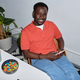 Black adult man using smartphone while relaxing at workplace and smiling - PhotoDune Item for Sale