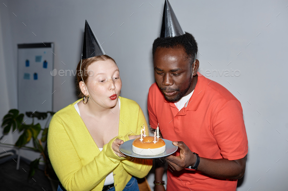 People celebrating birthday in office and holding cake - Stock Photo - Images