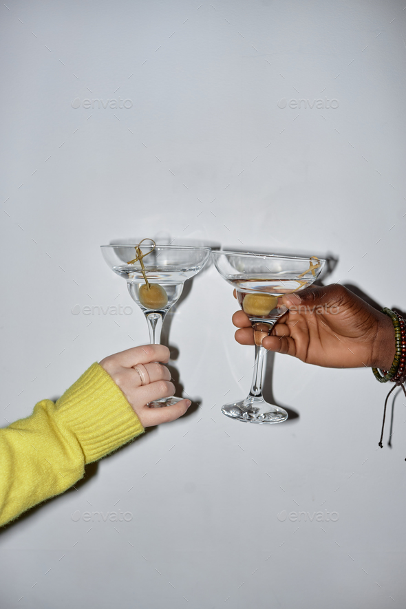 Closeup of two young people holding glasses and toasting with martini - Stock Photo - Images
