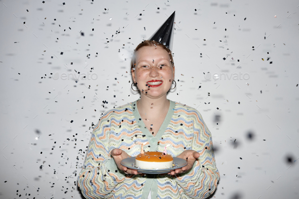 Young woman holding Birthday cake with confetti shower - Stock Photo - Images
