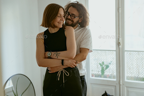 Smiling couple hugging and enjoying time together while standing at home. Good relationship time - Stock Photo - Images