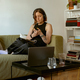 Woman freelancer sitting at her sofa and using smartphone and laptop while working from home - PhotoDune Item for Sale