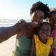 Portrait of african american multi-generation family enjoying at beach against sea and sky in summer - PhotoDune Item for Sale