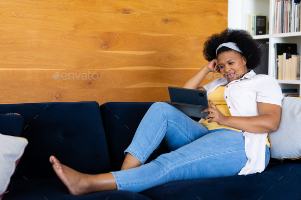 Happy Plus Size African American Woman Relaxing On Sofa And Using