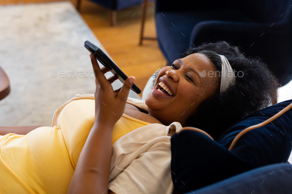 Happy Plus Size African American Woman Lying On Sofa Talking On