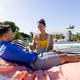 Caucasian young woman having beer and talking with boyfriend lying on lounger at tourist resort - PhotoDune Item for Sale