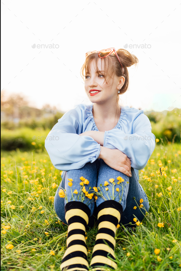 Young woman wearing blue blouse, jeans and striped black and yellow socks with flowers inside