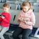 Children, kids, girls waiting for plane flight in departure hall. Sitting on chairs, playing  - PhotoDune Item for Sale