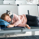 Kid, teen tired girl sleeping, waiting in airport passenger terminal departure hall with backpack.  - PhotoDune Item for Sale