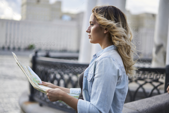 Caucasian female tourist holding paper map choosing direction route on vacations