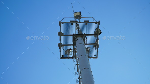 High lighting mast against the blue sky. View from below. Full height.