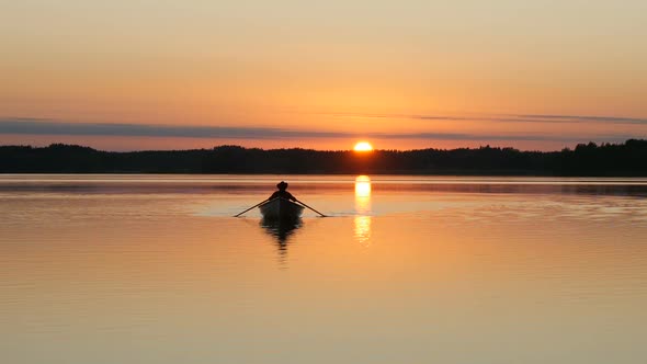 Beautiful Sunset Over Lake and Man Rowing on Boat