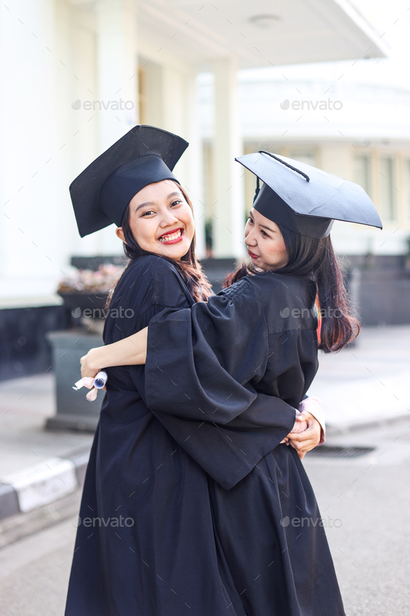 Two women students hugging on graduation day. - Stock Photo - Images