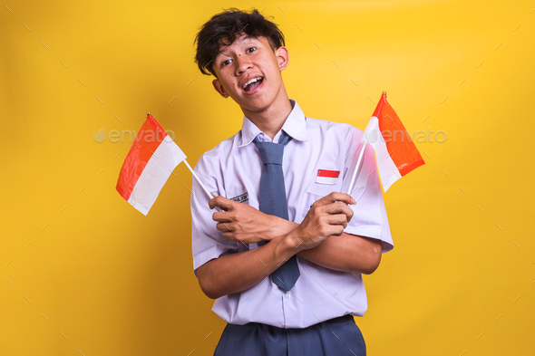 Indonesian high school student man waving flags of Indonesia, celebrating the independence day. - Stock Photo - Images