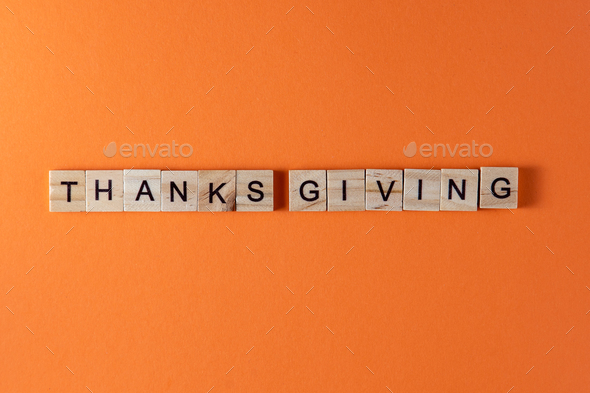 Thanksgiving word phrase in wooden letters. Motivation and slogan. Orange background