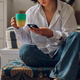 Woman using smartphone and drinking coffee while sitting on a floor at home - PhotoDune Item for Sale