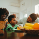 A happy diverse family is sitting at the breakfast table at home and spending time together. - PhotoDune Item for Sale