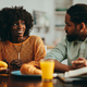 An african american man is sitting with his wife at the breakfast table at home and talking to her. - PhotoDune Item for Sale