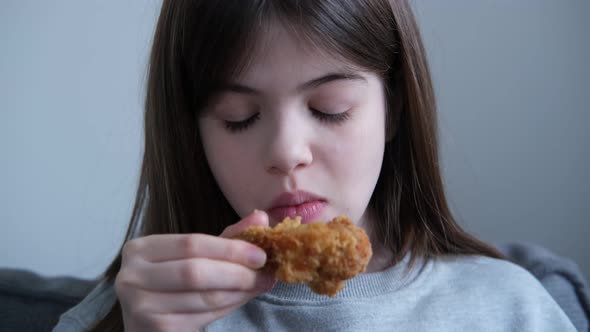 Little Girl Teenager Eating a Chicken Leg Drumstick at Home Not Healthy Food Fast Food Concept