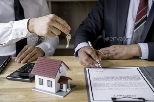 Real estate agent hand over the keys during meeting after signing rental lease contract or sale purc