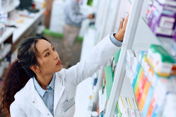 Young Chinese female pharmacist working in drugstore.