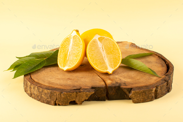a front view sliced lemon and whole with green leaves on the wooden brown desk isolated fresh juicy