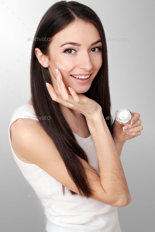 Woman with multiple shades of foundation on her face on grey background