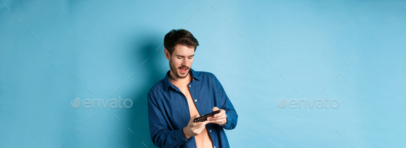 Young guy playing video game on mobile phone, tilt body and holding smartphone horizontally