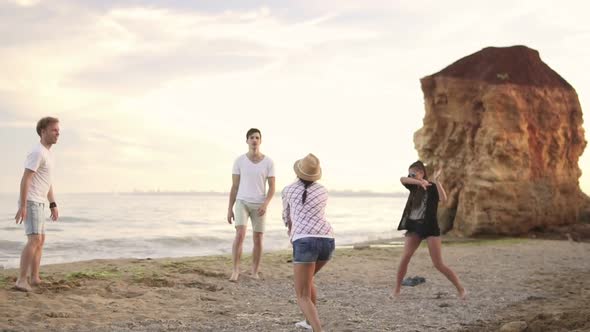 Joyful Young Friends Playing Volley Ball on the Beach By the Sea in the Evening alt