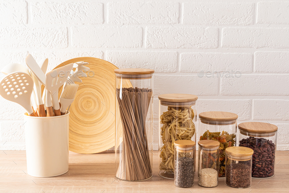 Glass jars with a bamboo lid for storing bulk products and spices on a wooden countertop