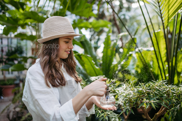 Portrait of beautiful female gardener taking care of plants in botanical garden.