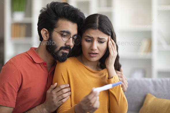 Unwanted Pregnancy. Worried young indian couple looking at positive test
