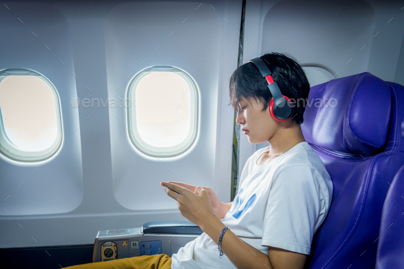 Young happiness tourist teenager passenger flight seat near window using taplet app relax litsening