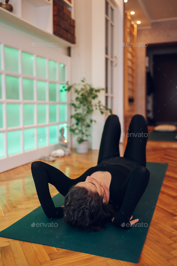 young beautiful, flexible girl doing yoga pose, stretching in a cozy, sunny  room Stock Photo