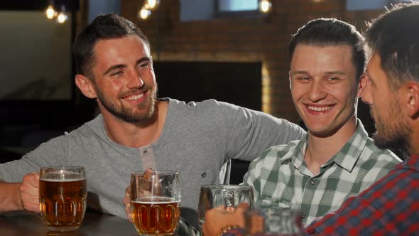 Group of Male Friends Clinking Beer Glasses and Drinking at the Bar alt