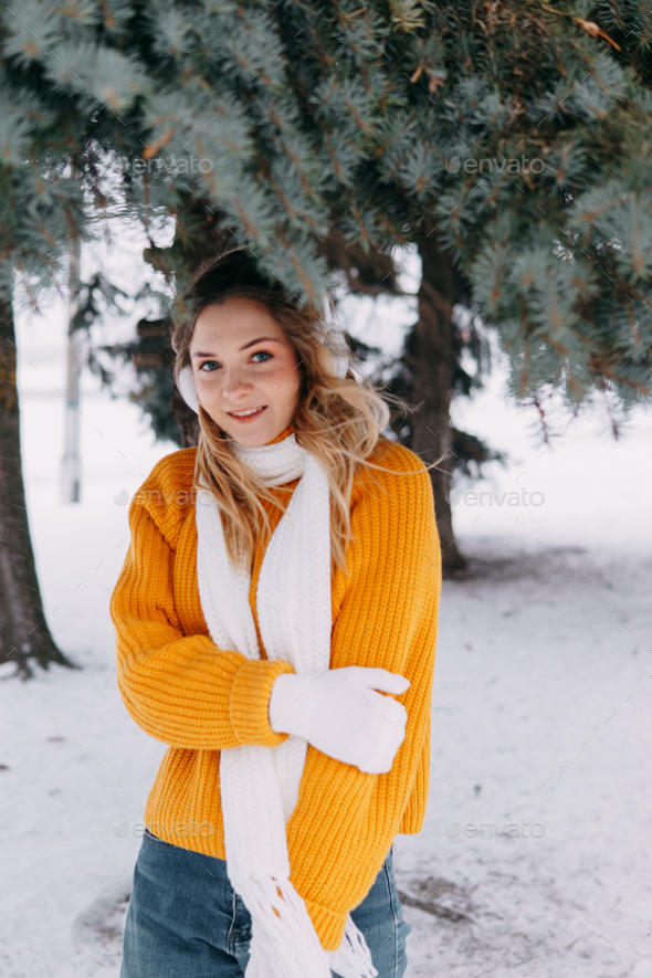 Teen blonde in a yellow sweater outside in winter. A teenage girl on a walk  in winter clothes Stock Photo by Annu1tochka