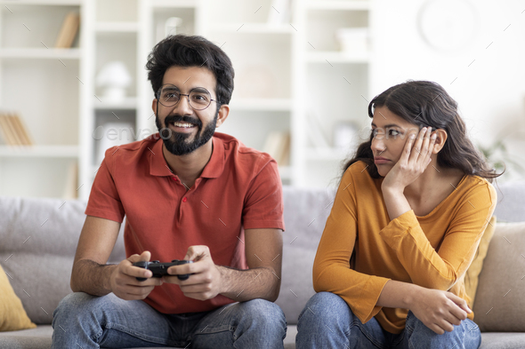 Happy boyfriend and girlfriend playing video games and holding