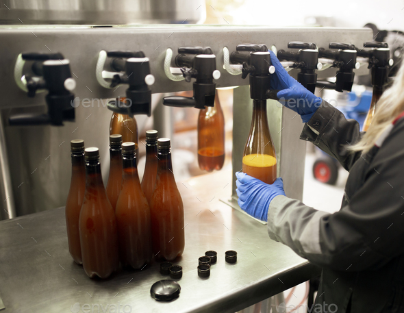 an employee on the factory filling new plastic bottle with beer from faucet