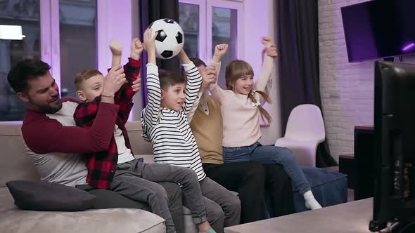 Family Football Fans Sitting on the Sofa at Home and Celebrating the Victory alt