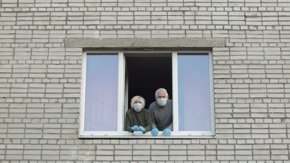 Old Grandparents Stay at Window Isolated at Home on Quarantine. Coronavirus alt