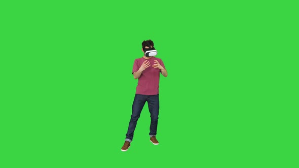 Amazed Man Using VR Headset Glasses Touching and Interacting with Virtual Reality World on a Green alt