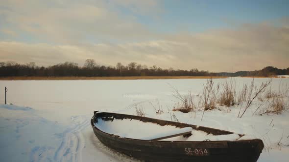 Wooden boat by a frozen river in winter