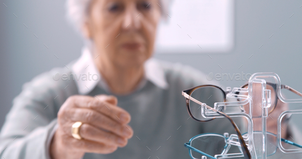 Elderly woman trying new glasses at the optician shop